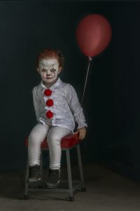 A low key photograph of a young girl dressed as a clown