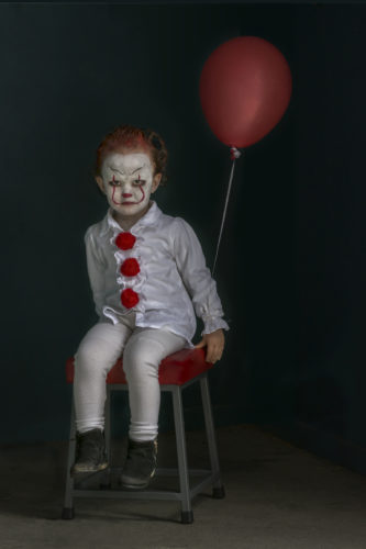 A low key photograph of a young girl dressed as a clown