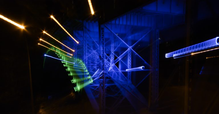 Abstract photo of Hamilton bridge at night showing the blue, green and yellow street lighting in streaks