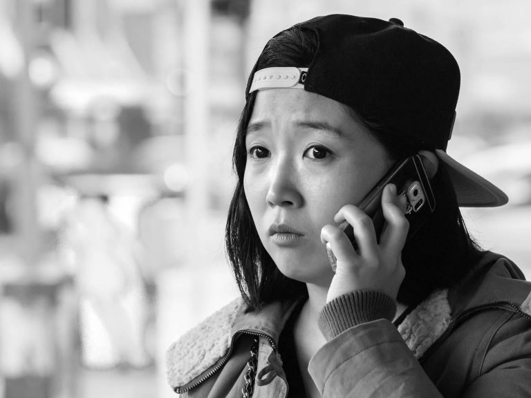 A photo of a young lady on her phone while out in a public area