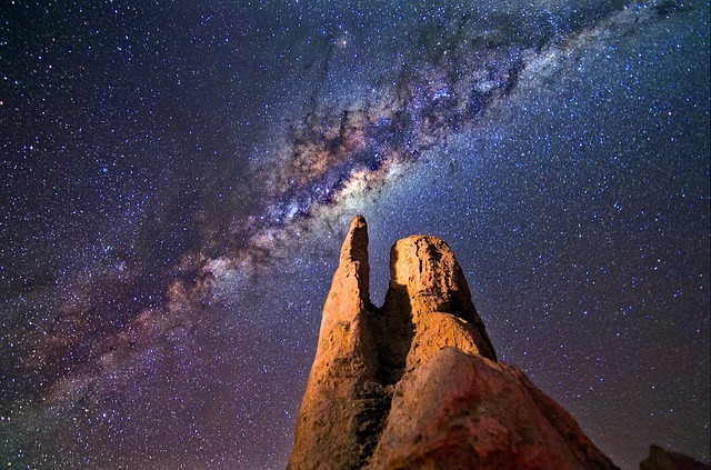 A photograph of the milky way with huge rocks composition in foreground highlighted with light painting