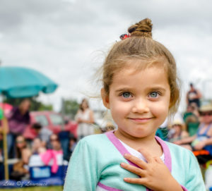 A portrait of a smiling 3 year old girl with the prettiest sea blue/green eyes