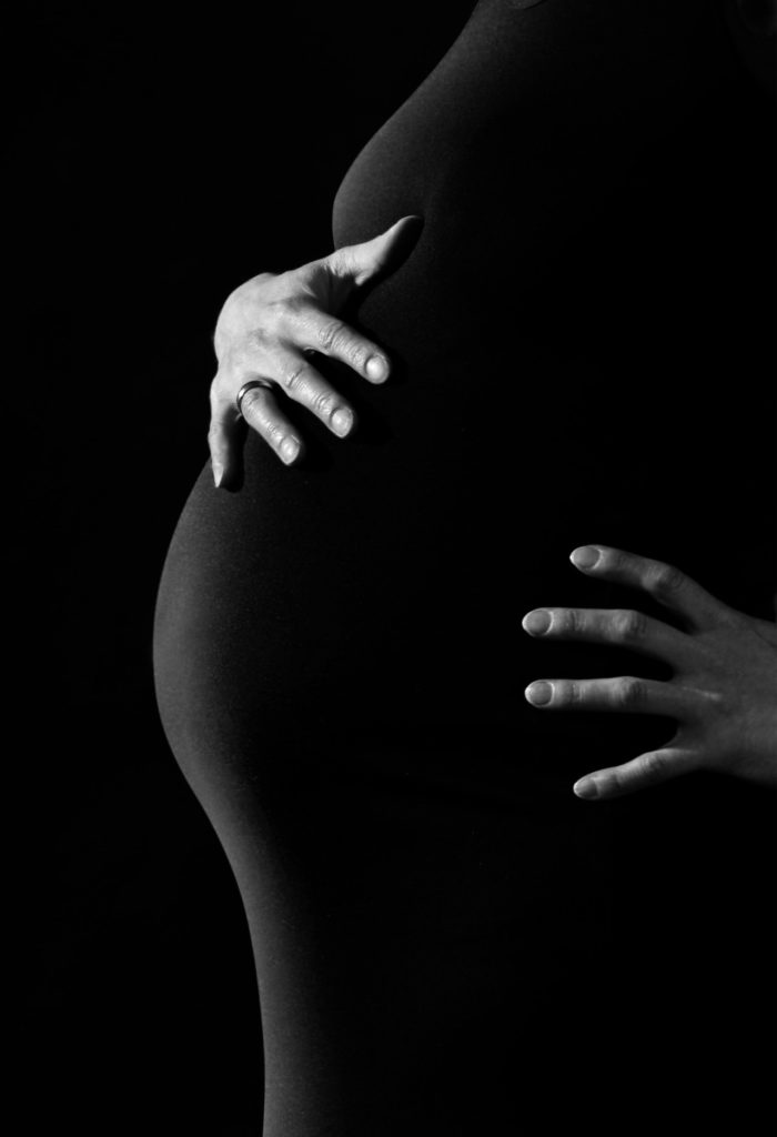 Gorgeous photo of the baby hump with expectant mother's hands caressing the top of the bump